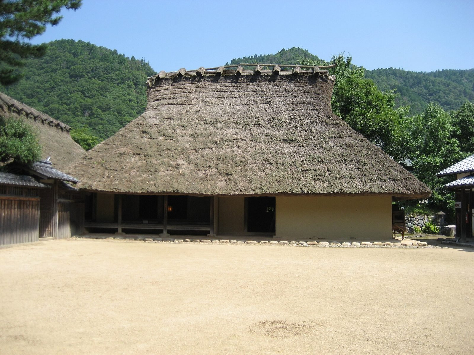 Casa minka tradicional con tejado de paja y montañas